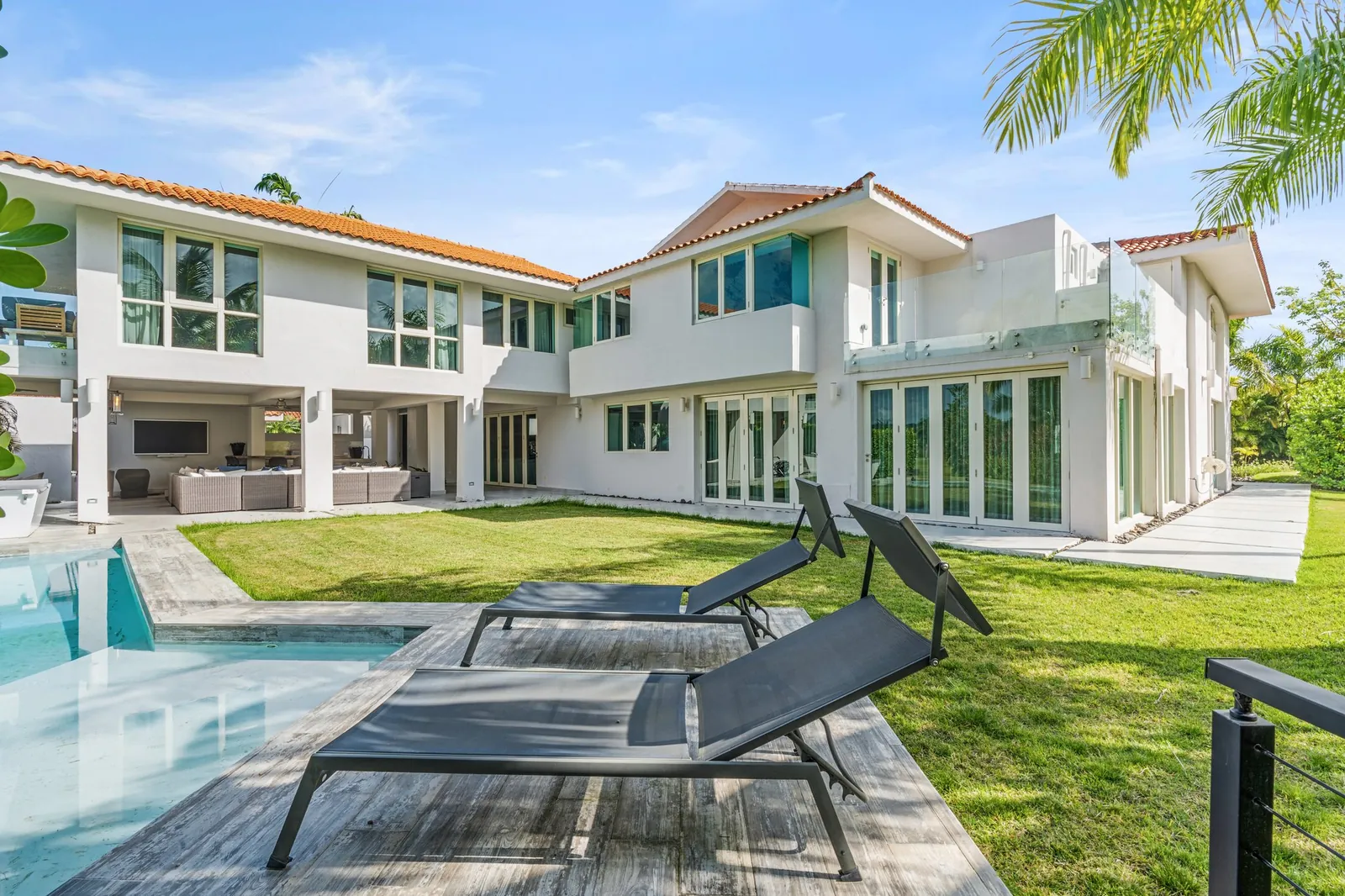 White two-story home with a terracotta roof, pool and lawn