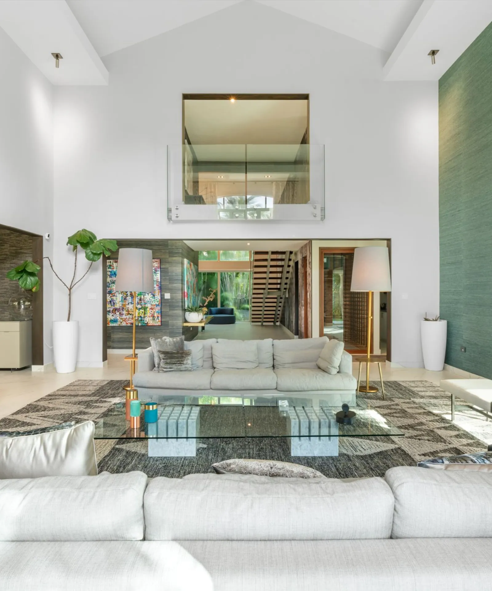 Double-height living room with pale sofas and an upper glass balcony