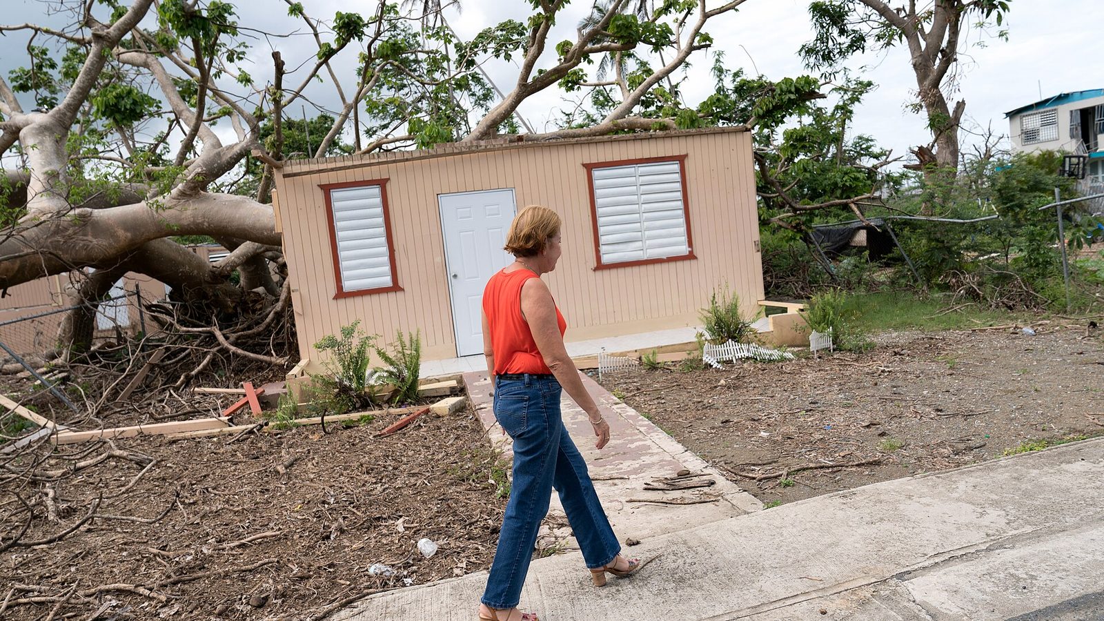 Julia Nazario Fuentes, Mayor of Loiza, walking past a damaged house in Loíza, Puerto Rico