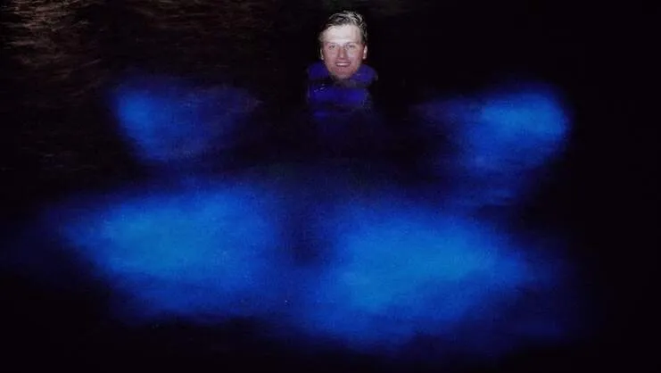 imagen de un hombre nadando en la bahía bioluminiscente