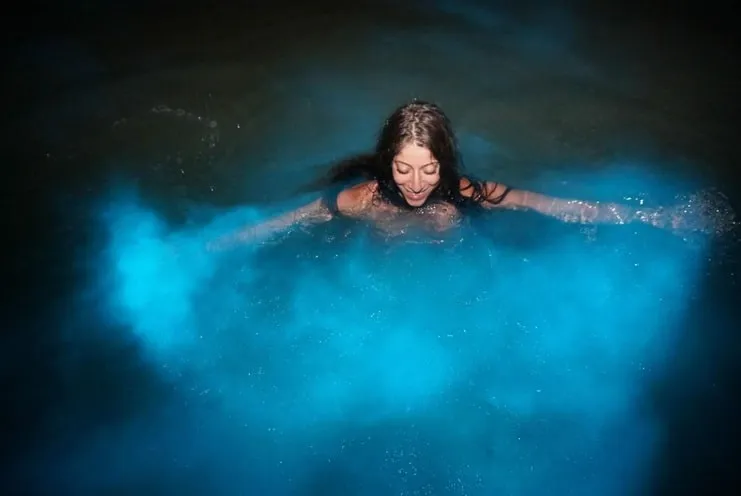 imagen de una mujer nadando con bioluminiscencia