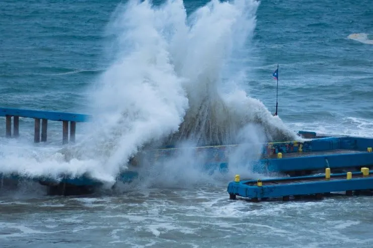 Una ola rompiendo contra el muelle de Crash Boat