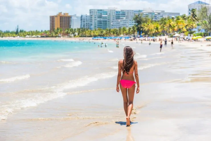 Mujer caminando sola por la orilla de una playa urbana