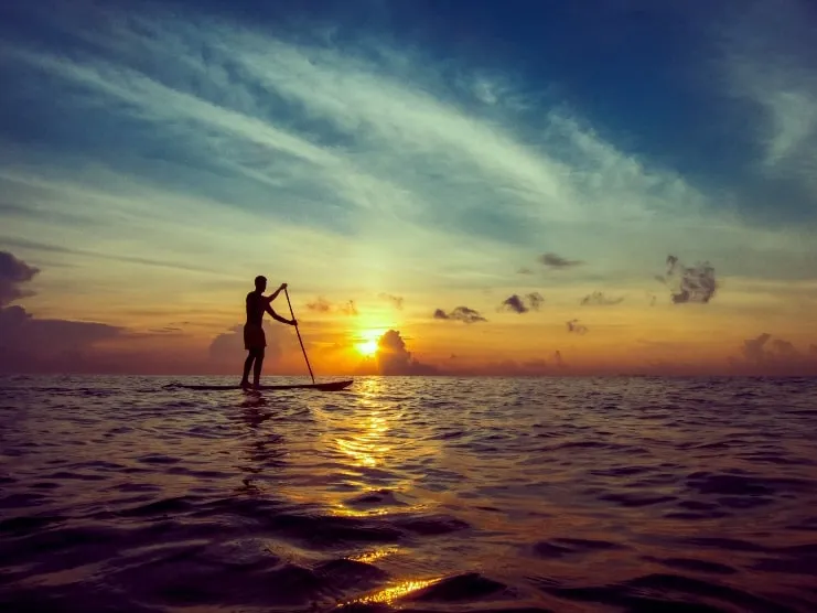 Persona haciendo paddleboard al atardecer