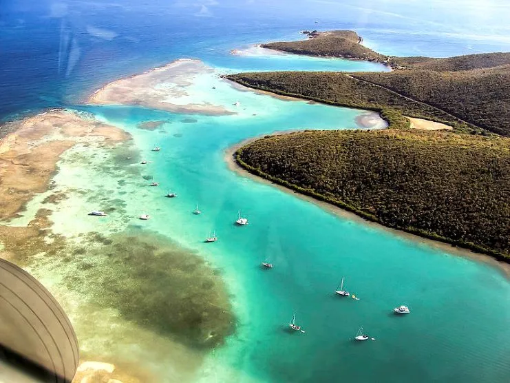 Vista aérea de aguas turquesa con veleros anclados entre colinas verdes en Culebra