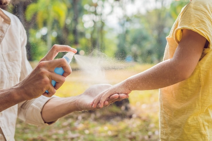 image of a mother spraying mosquito repellent